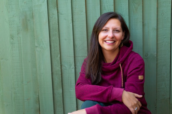 Hannah Smith wearing red jumper in front of green wood fence